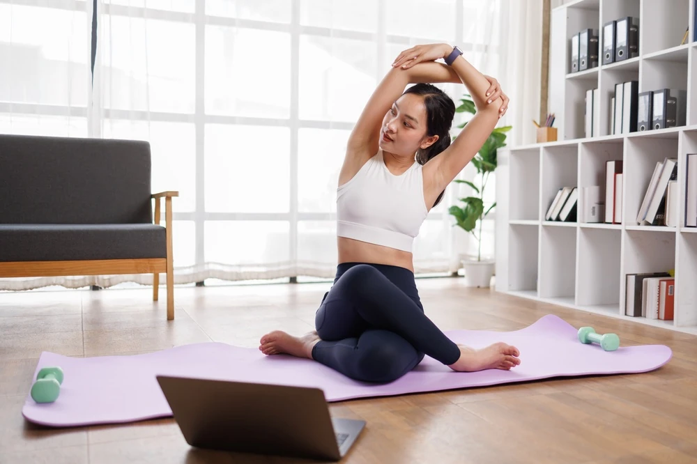 Woman stretching on a yoga mat at home