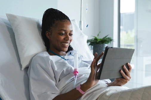 Patient in a hospital bed using a tablet